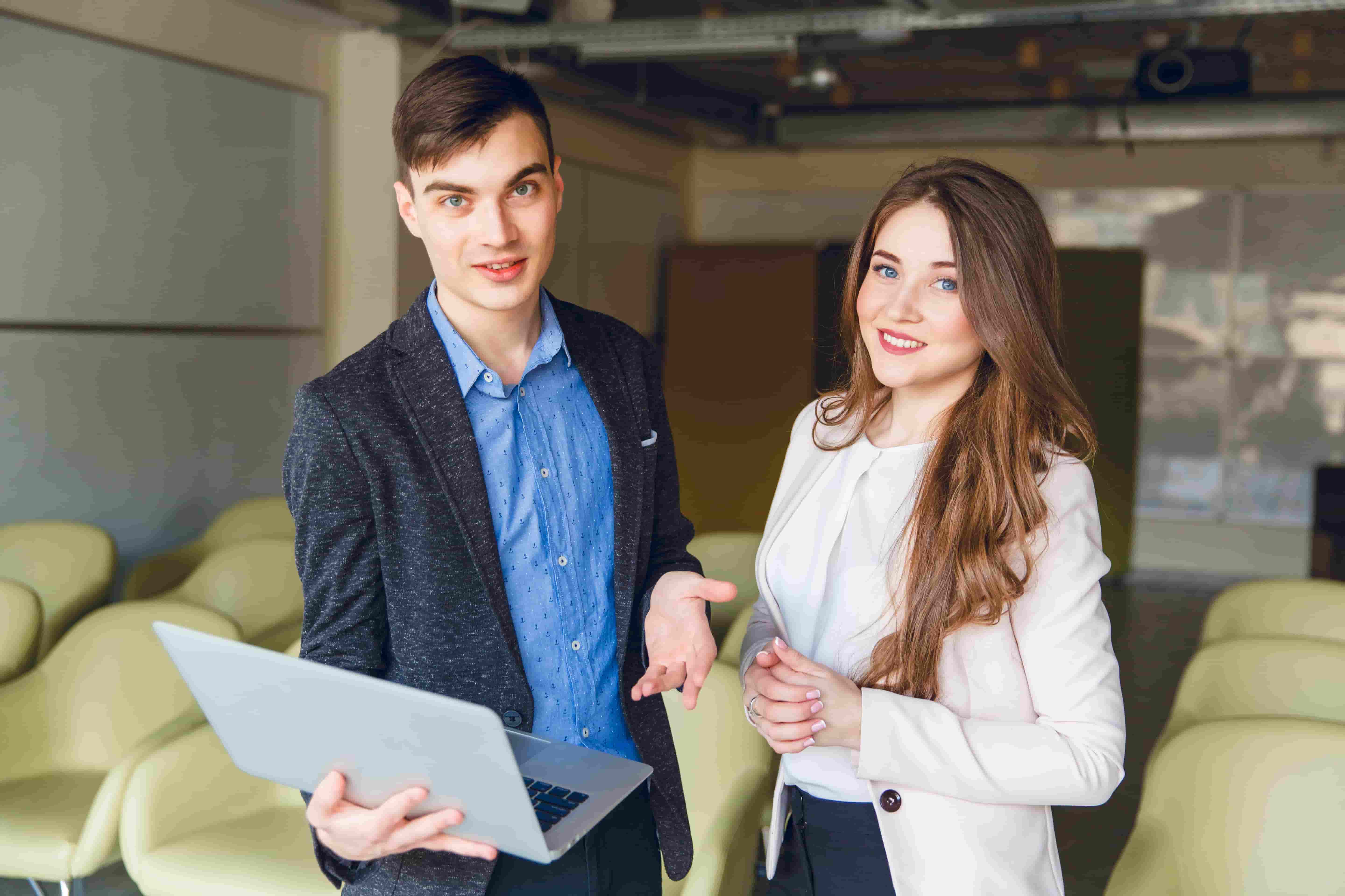 Young man and woman in office setting with laptop