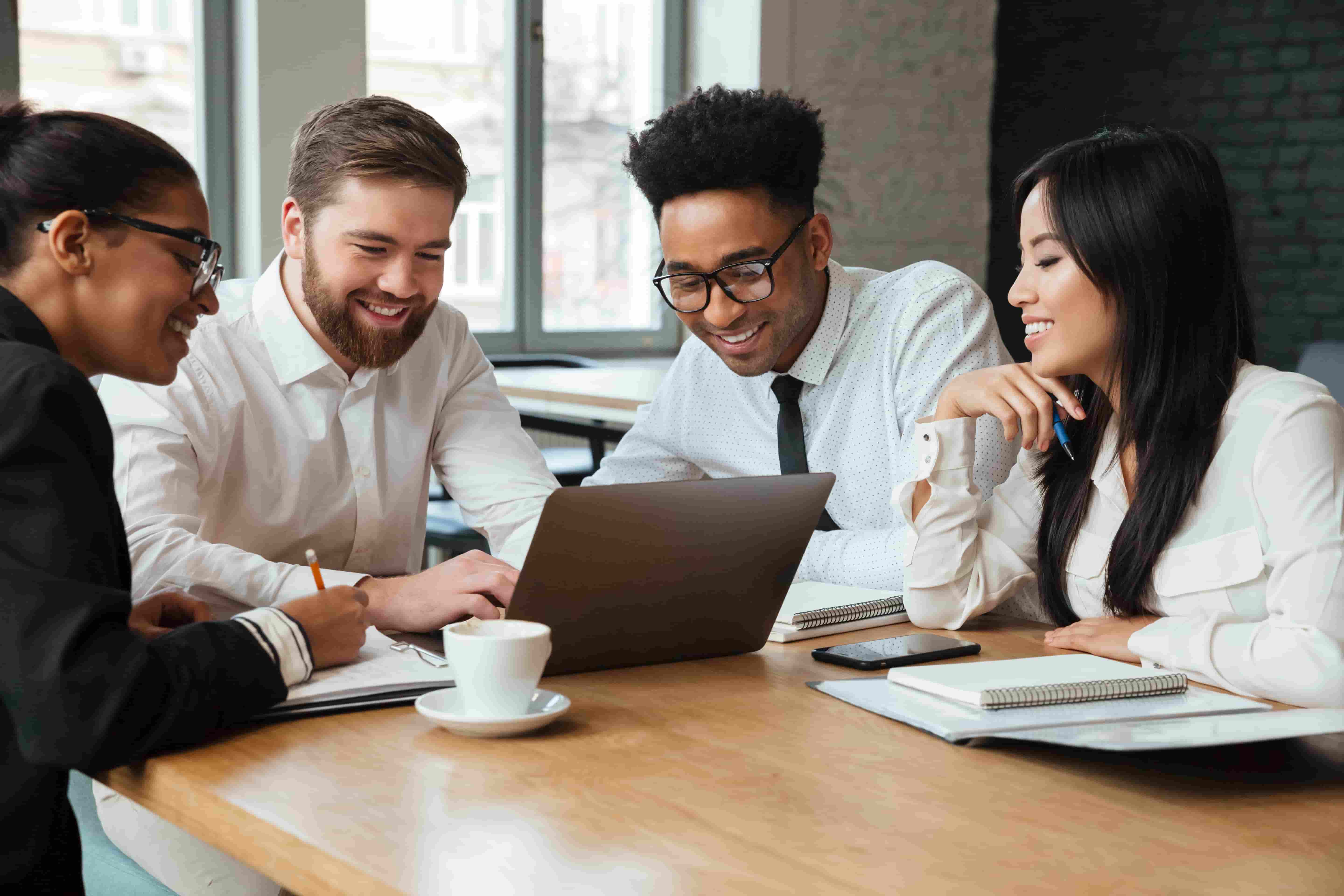 Group of people around table looking at laptop